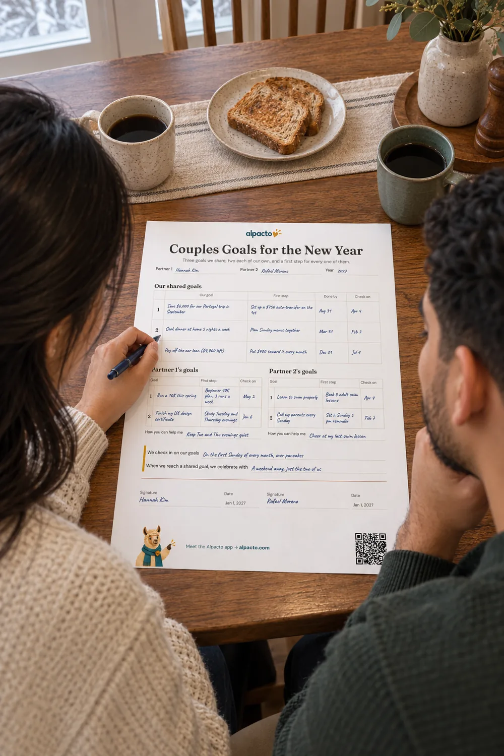 A couple at a wooden table fills in the couples goal setting worksheet for the new year, minimal design, coffee and toast beside it.