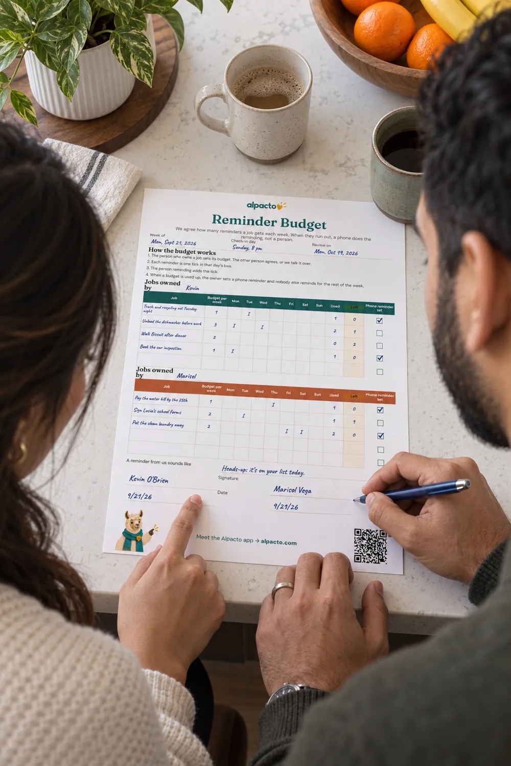 A couple seen from behind at a breakfast bar, he holds a pen by the signatures on the filled-in reminder budget while she points at a line