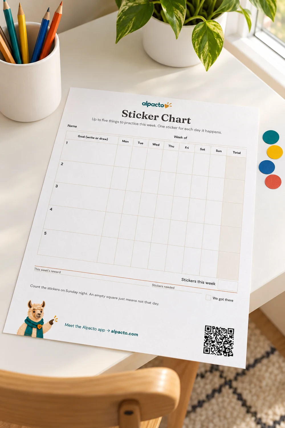 A blank printable sticker chart for kids on a desk, with a sheet of stickers beside it.